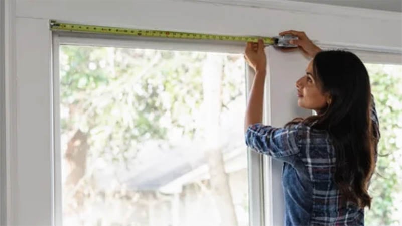 Woman measuring for window blinds